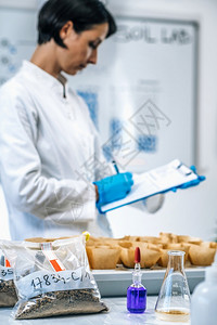 土壤样本检测实验室关闭身着白大衣的女科学家在实验室作笔记的图像图片