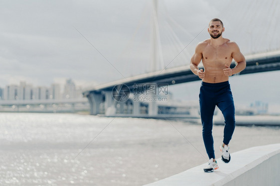 早在河附近奔跑表现出决心有肌肉的身体穿着积极服饰呼吸新鲜空气图片