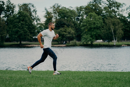 奔跑在河边的男子步全长镜头享受速度运动拍照穿着积极服饰带生活方式运动员迅速跑步接受心动训练图片