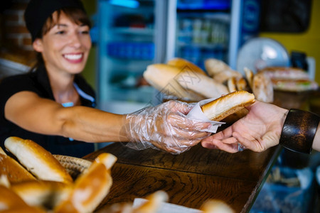 女微笑的面包店工人给顾客吃鸡肉背景图片