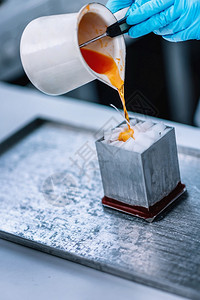 将橙色麦芽蜡倒入铝质模具里面装满白蜡立方体特殊的蜡烛制作过程图片