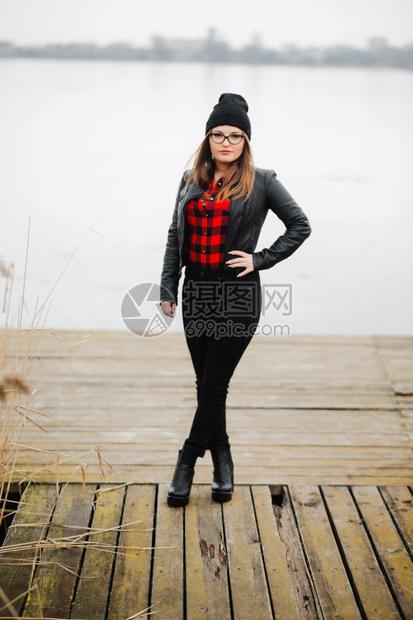 穿着皮夹克的女孩站在湖边桥上图片