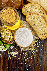 面粉碗中的绿麦粉盘上打麻勺子和桌上小吃玻璃罐中的油面包新鲜花和黄麦叶其背景是上面的黑木板图片