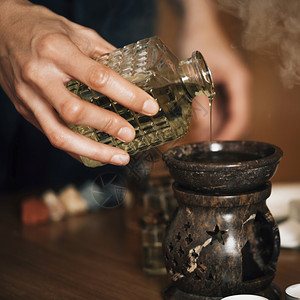 Ayurveda芳香疗法按摩女手将芳香油倒入一个必要的石油扩散器中芳香疗法按摩将芳香油倒入必要的石扩散器中图片