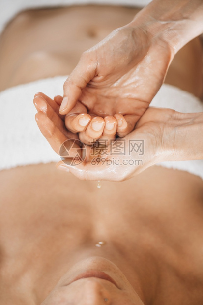 Ayurvedic芳香疗法油按摩师持有用于身体按摩的Ayurveda油图片