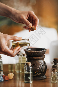 Ayurveda芳香疗法按摩女手将芳香油倒入一个必要的石油扩散器中芳香疗法按摩将芳香油倒入必要的石扩散器中图片