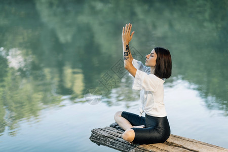 在湖边坐着莲珠和冥想的女图片