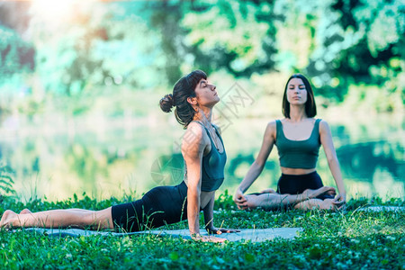 在水下冥想莲花姿势妇女做瑜伽教练帮助妇女做头部姿势在水下做手莲花姿图片