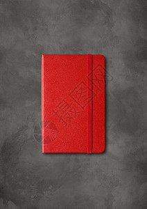 在暗混凝土背景上隔离的红色封闭笔记本模型深混凝土背景上的红色封闭笔记本图片