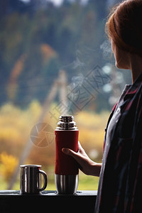 一个女孩在山地背景下从热水池里倒茶图片