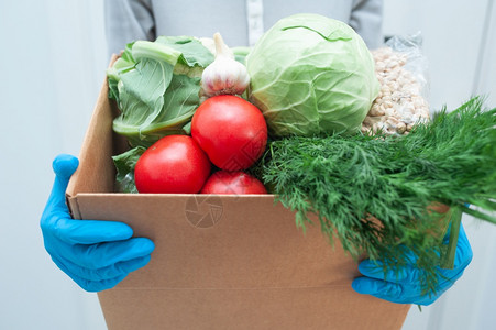 身戴手套的志愿者持有食物捐赠箱的蔬菜以帮助病人或穷身戴手套的志愿者持有食物捐赠箱的蔬菜来帮助病人或穷图片