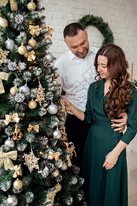 新年情人节爱浪漫的概念庆祝圣诞节年轻夫妇的假期衣服拥抱在圣诞树附近浪漫的概念背景图片