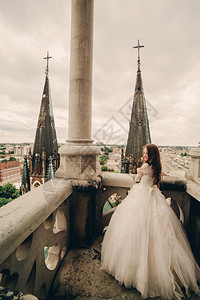 美丽的新娘站在古老哥特大教堂阳台上图片