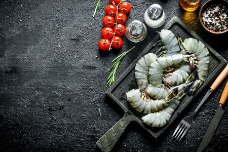 生虾和樱桃西红柿香料的切菜板上图片