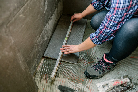 无法识别的女砖匠用一层检查地板安装瓷砖女匠用一层检查地板图片