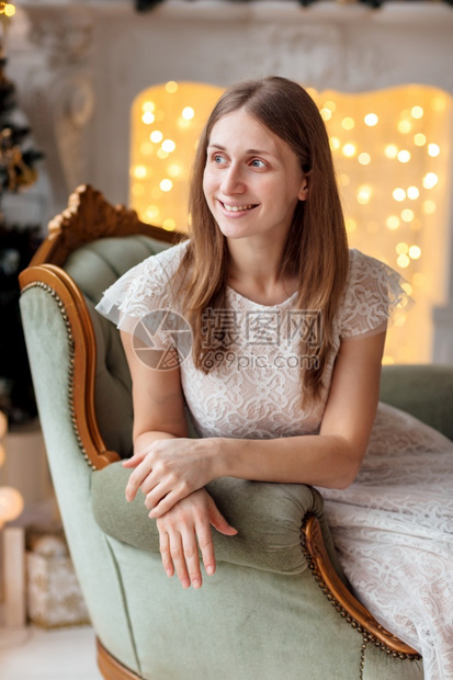 美丽而愉快的黑发女孩带着开放的笑容坐在圣诞树附近的美丽椅子上新一年装饰品假日概念开着微笑的漂亮而愉快黑发女孩坐在圣诞树附近的漂亮图片