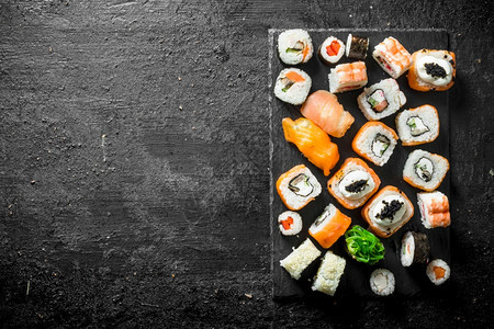 一套不同的寿司卷配有三文鱼鸡虾和蔬菜黑色生锈背景的虾和蔬菜图片