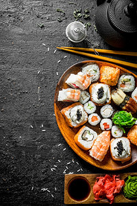 新鲜的寿司和卷子配有酱汁和绿茶黑色生锈背景图片