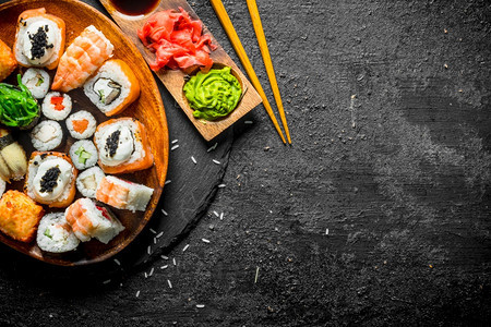 传统的日本卷和寿司放在一块石板上的子黑色生锈背景传统的日本卷和寿司放在一块石板上的子图片