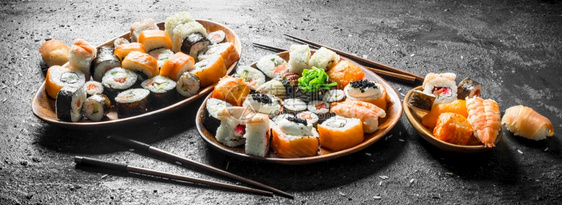 不同种类的日本寿司卷配有鲑鱼虾和蔬菜黑生化背景图片