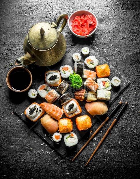 各种日本寿司卷配有姜汁和酱油黑色生锈背景图片