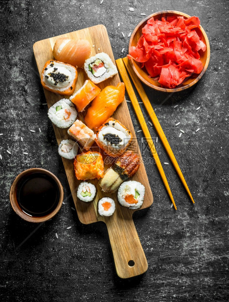 各种类的寿司豆和卷子包括姜汁和酱以及深红的生锈背景各种类的寿司豆和卷子还有姜汁和酱图片
