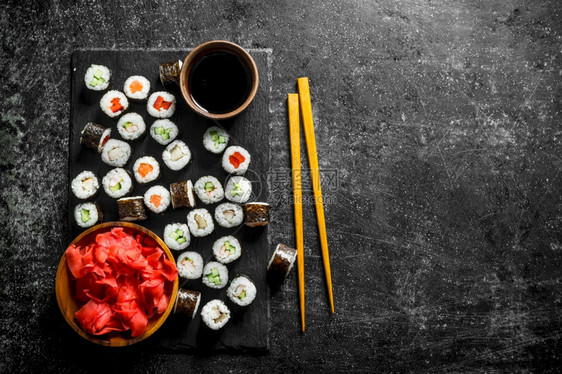 寿司卷在一块石板上面有酱油和姜汁深黑的生锈背景图片