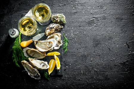 鲜生牡蛎在石板上白葡萄酒黑色生锈背景新鲜牡蛎在白葡萄酒的石板上图片