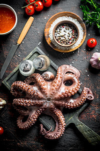 有大蒜和香料的剪切板上章鱼黑暗生锈背景上章鱼带大蒜和香料的剪切板上章鱼图片