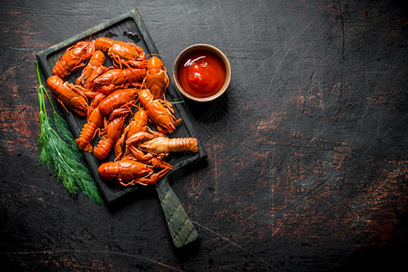 新鲜龙虾切鱼板上煮熟的龙虾和番茄酱黑生化背景烤熟的龙虾和番茄酱背景