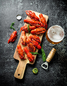 红煮龙虾在有啤酒的切割板上深生背景图片