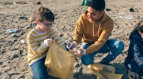 年轻志愿者在海滩上捡垃圾图片