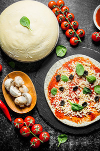 生披萨番茄糊蘑菇橄榄和辣椒的面粉黑色生锈背景的辣椒番茄糊橄榄和辣椒的面粉图片