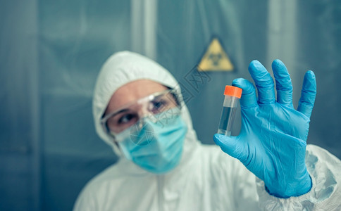 有细菌保护西装的女科学家在实验室监视小瓶图片