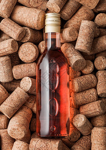 在各种葡萄酒软木背景之上的粉红玫瑰酒瓶子宏图片