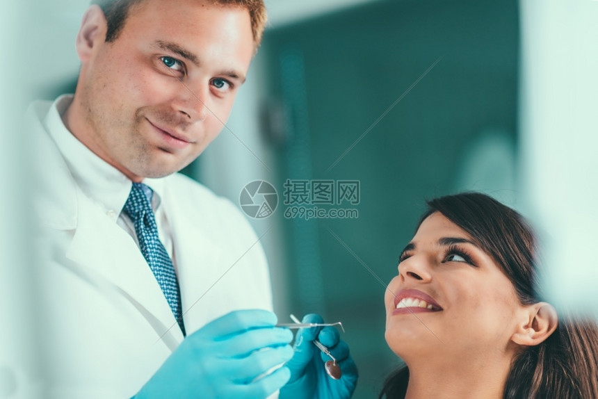 与年轻女病人一起工作的牙医图片