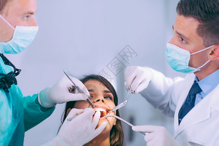与年轻女病人合作的牙医图片