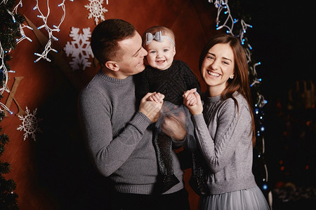 快乐的圣诞节和新年日快乐可爱的年轻家庭父亲母亲和小女儿在圣诞节背景上拥抱和亲吻
图片