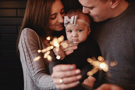幸福家庭母亲父和有火花光线的女婴肖像期待圣诞节的家庭选择照片幸福家庭父亲和有火花光线的女婴肖像图片