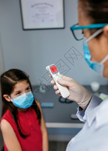 女儿科医生在对孩进行温度测试后对红外温度计进行观察图片