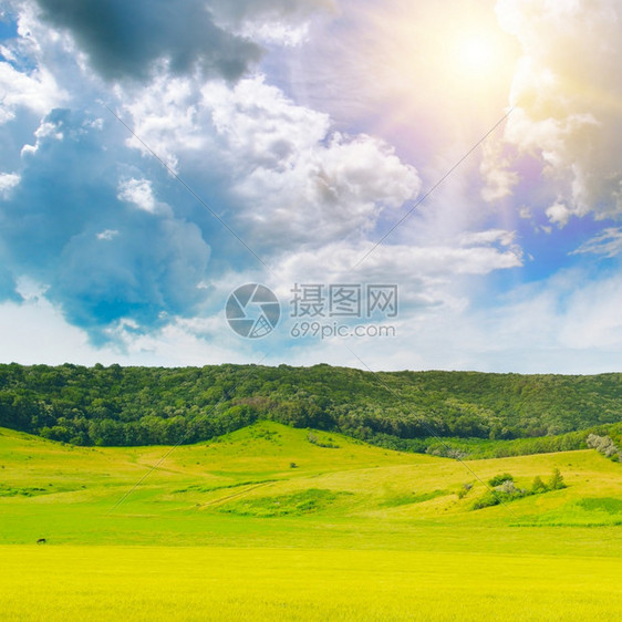 小山上绿草地蓝天空中云雾图片