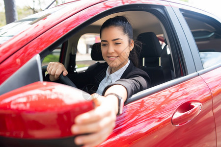 女驾驶员素材年轻女专业驾驶员在汽车中的肖像和移动后翼镜交通概念妇女在汽车中移动后翼镜背景