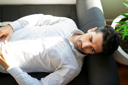 一名在治疗期间躺沙发上的年轻人被紧关上心理和健康概念男人在治疗期间躺沙发上图片