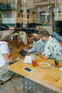 一群朋友坐在咖啡店里看着平板电脑坐在咖啡店里看平板电脑的朋友们图片