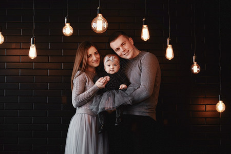 年轻家庭父亲母和女婴的肖像在家里享受时间春光灯泡在前景圣诞节时间年轻家庭父亲母和女婴的肖像在家里享受时间图片