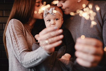 幸福家庭母亲父和有火花光线的女婴肖像期待圣诞节的家庭选择照片幸福家庭父亲和有火花光线的女婴肖像图片
