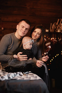 可爱的年轻家庭父亲妈和小姑娘床上有火花和圣诞节背景后面有圣诞背景图片