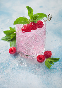 蓝色背景上带草莓冰和薄荷的粉红色柠檬鸡尾酒图片