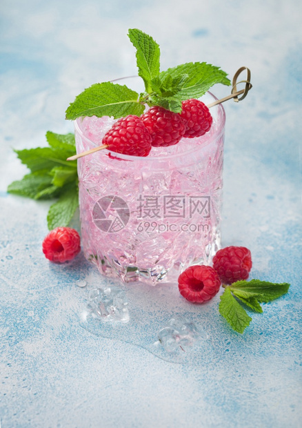蓝色背景上带草莓冰和薄荷的粉红色柠檬鸡尾酒图片
