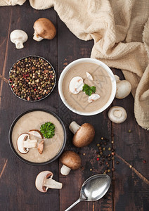 瓷碗盘奶油椰子辣椒蘑菇汤勺子胡椒和厨房布在黑木板上图片